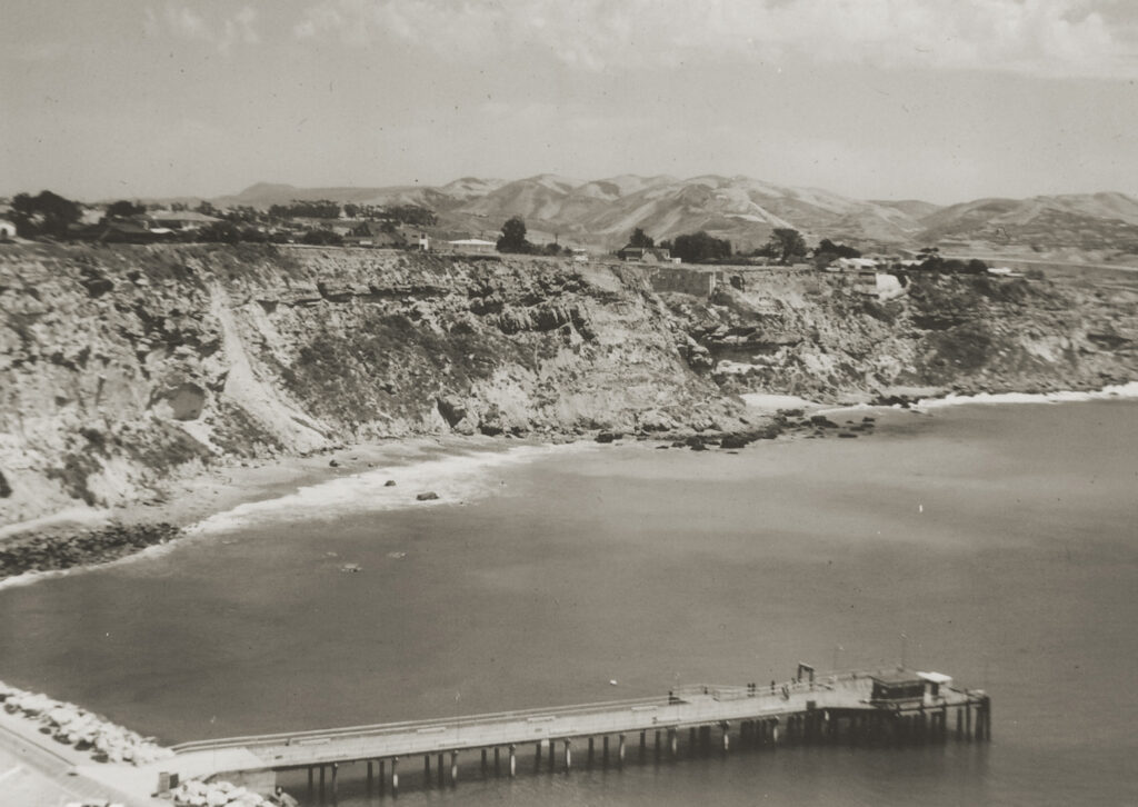 historic California coastal scene of harbor, cliffs, pier and blufftop homes