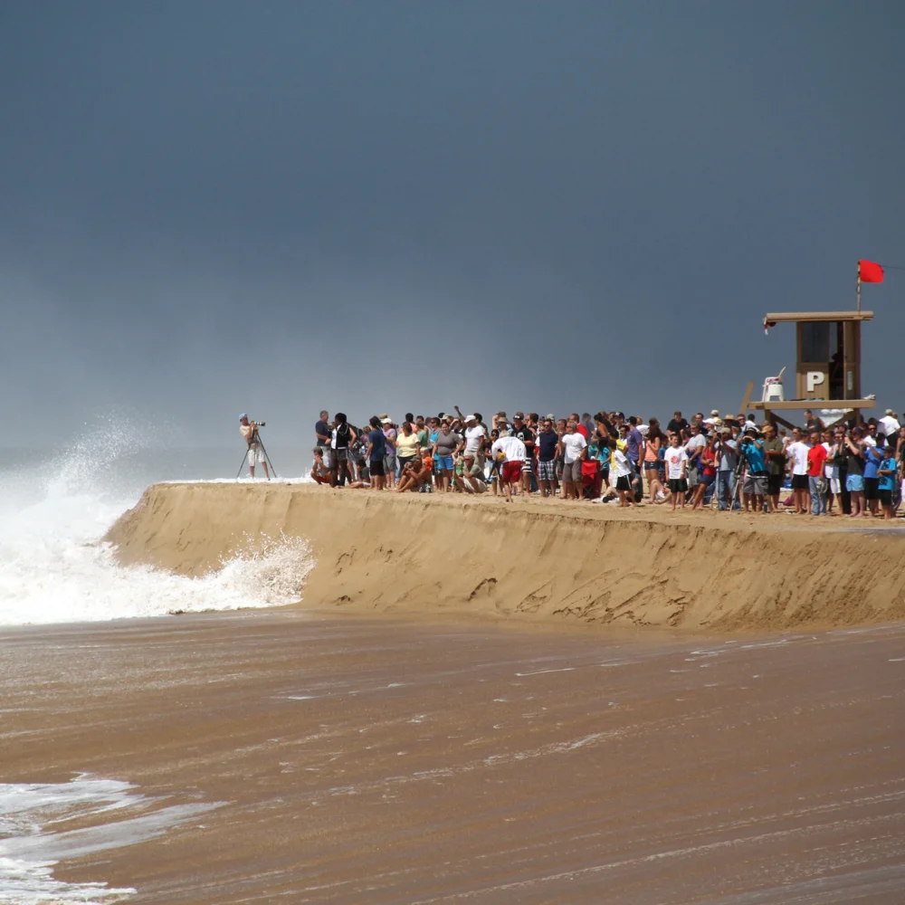 people gathered on beach to watch surfers